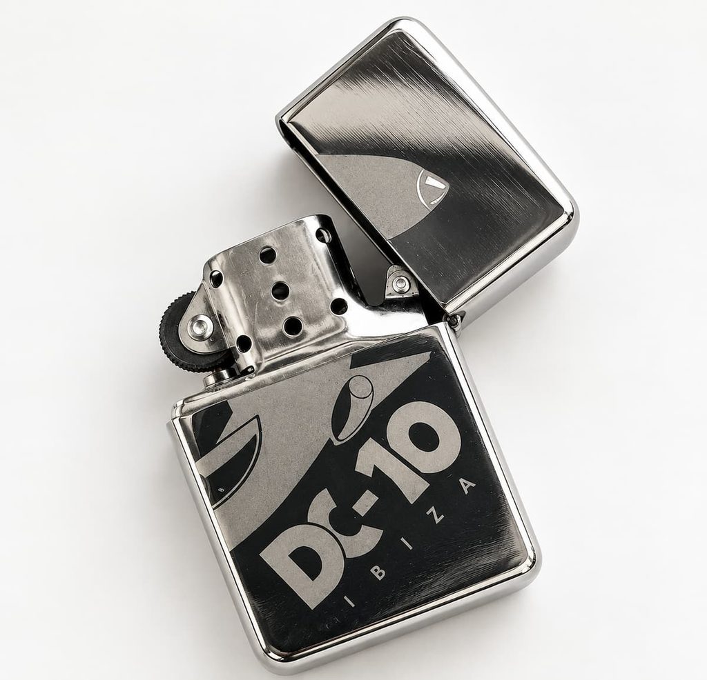 Encendedor metálico cromado Zippo personalizado para DC-10 Ibiza, abierto y con el mecanismo visible
